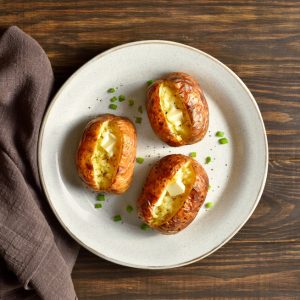 Oven,Baked,Potato,With,Butter,On,White,Plate,Over,Wooden